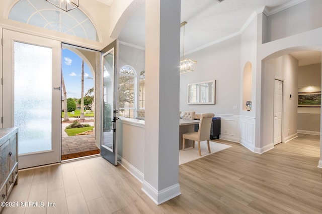 foyer featuring crown molding, light hardwood / wood-style floors, and a chandelier