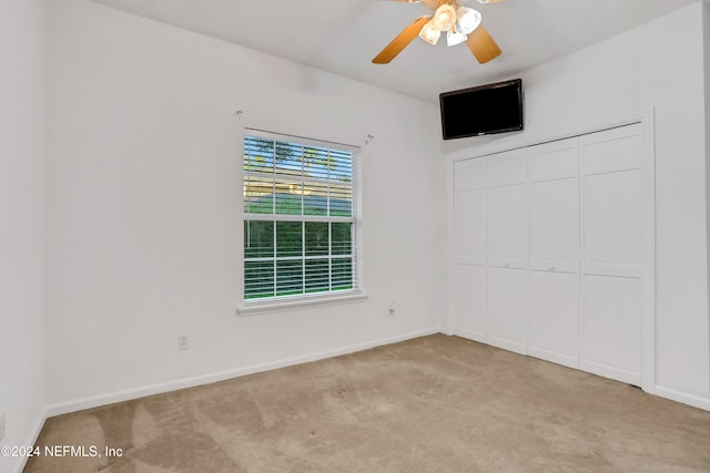 unfurnished bedroom featuring a closet, light colored carpet, and ceiling fan