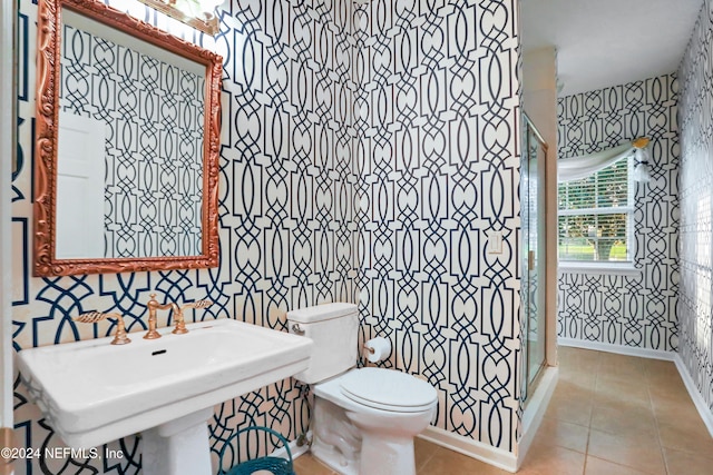 bathroom featuring a shower with door, toilet, and tile patterned floors