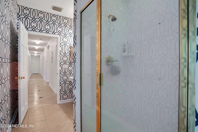 bathroom with a shower with door and tile patterned flooring