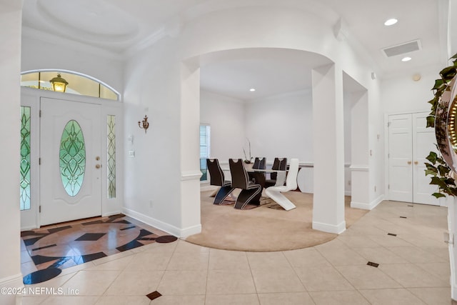 entrance foyer featuring a towering ceiling, ornamental molding, and light tile patterned floors