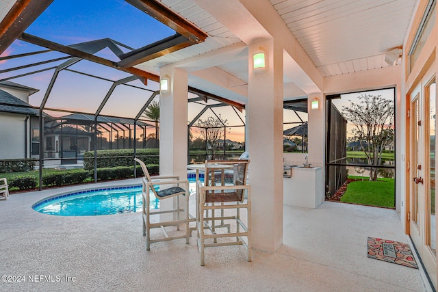 pool at dusk with a patio and a lanai