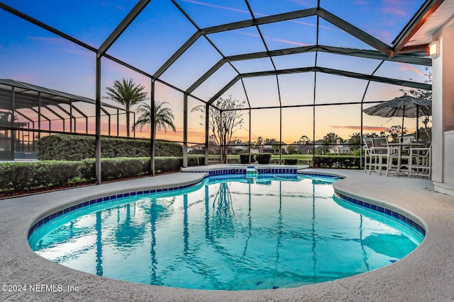 pool at dusk with a patio area and a lanai