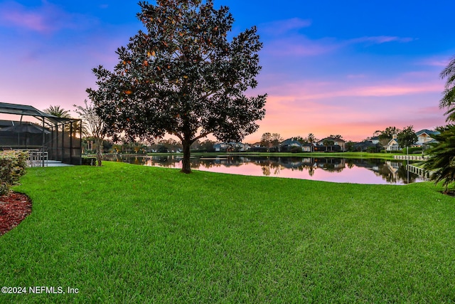 yard at dusk featuring a water view and a lanai