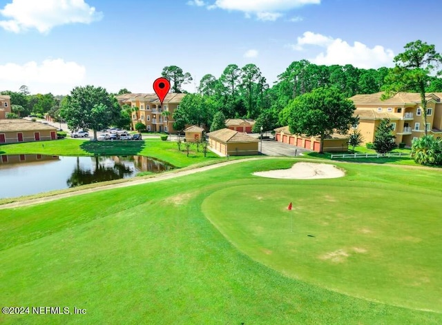 view of community featuring a lawn, a water view, and a garage