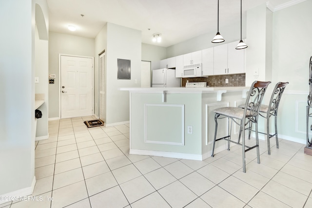 kitchen featuring electric panel, kitchen peninsula, white appliances, decorative light fixtures, and a breakfast bar area