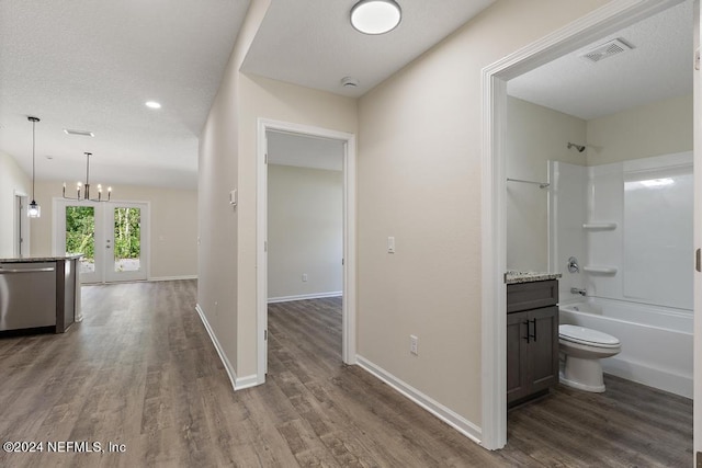 interior space with vanity, shower / bath combination, french doors, hardwood / wood-style flooring, and toilet