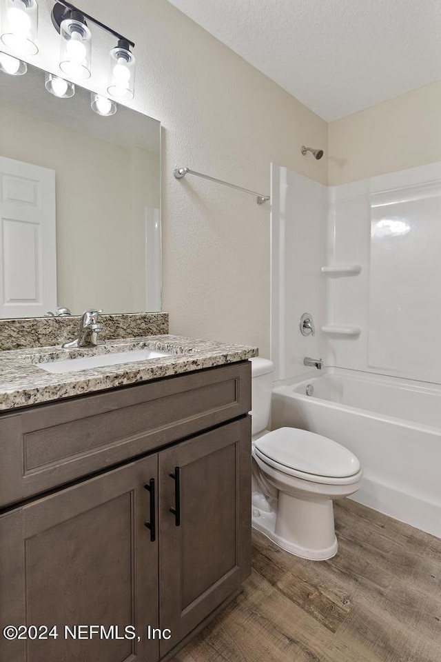 full bathroom featuring shower / bathtub combination, a textured ceiling, hardwood / wood-style floors, vanity, and toilet