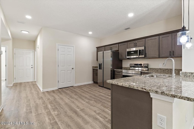 kitchen featuring dark brown cabinets, stainless steel appliances, light stone counters, and light hardwood / wood-style floors