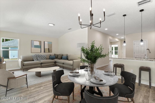 dining room featuring a textured ceiling, a chandelier, and light hardwood / wood-style floors