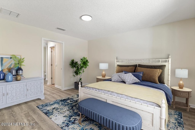 bedroom with light hardwood / wood-style flooring and a textured ceiling