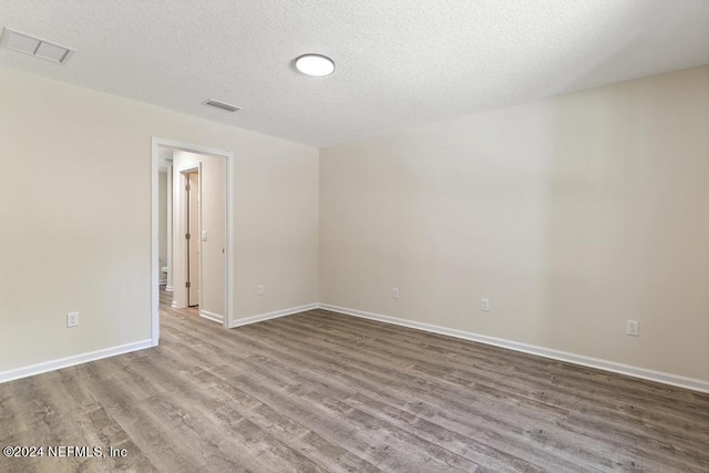 empty room featuring a textured ceiling and light hardwood / wood-style flooring