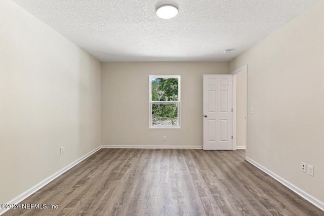 spare room with light wood-type flooring and a textured ceiling