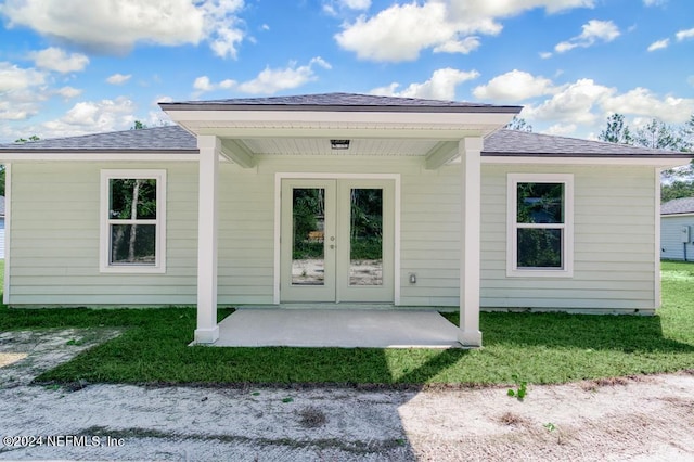 doorway to property featuring a lawn, a patio, and french doors