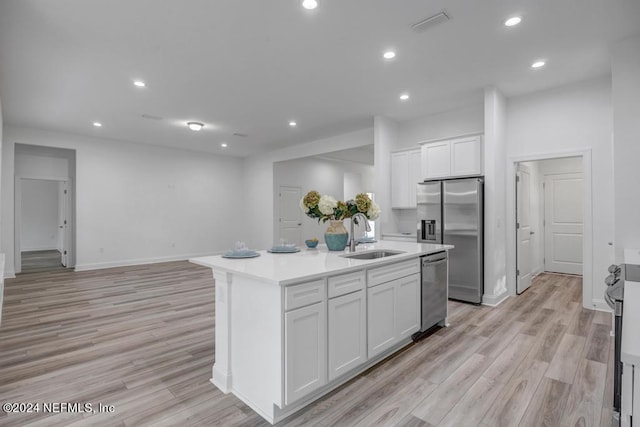 kitchen featuring white cabinetry, stainless steel appliances, light hardwood / wood-style flooring, a center island with sink, and sink