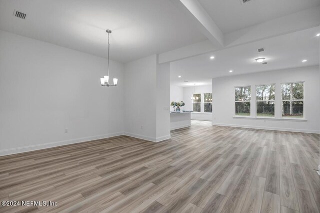 unfurnished living room featuring light hardwood / wood-style flooring, beam ceiling, and an inviting chandelier