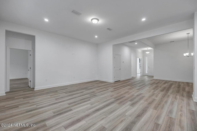 empty room featuring light hardwood / wood-style flooring and a chandelier