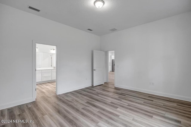 unfurnished bedroom with light wood-type flooring and ensuite bath