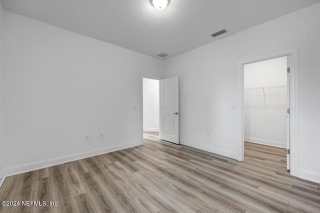 unfurnished bedroom featuring light hardwood / wood-style flooring, a closet, and a walk in closet