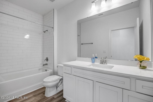 full bathroom with tiled shower / bath combo, hardwood / wood-style flooring, vanity, and toilet