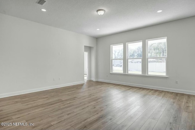 empty room with baseboards, recessed lighting, and light wood-style floors