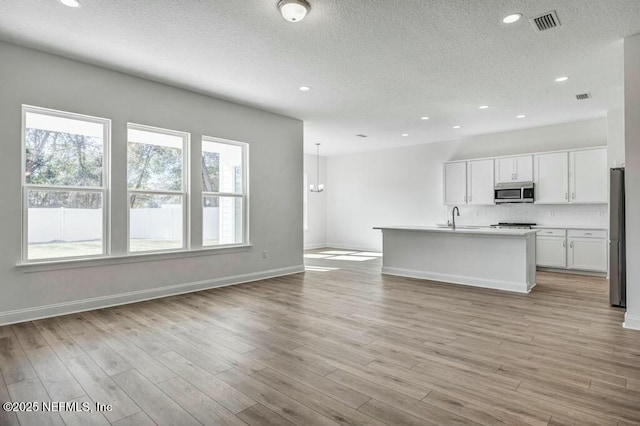 kitchen featuring stainless steel appliances, light wood finished floors, light countertops, and white cabinetry