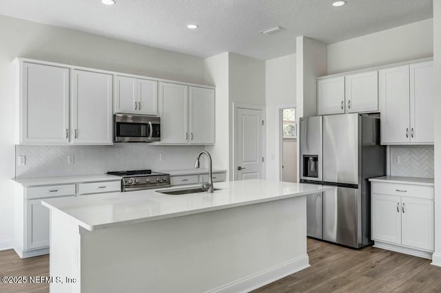 kitchen with stainless steel appliances, light countertops, white cabinets, and a sink