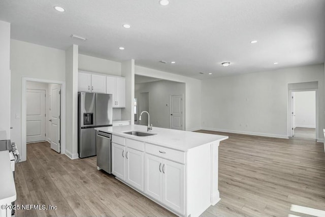 kitchen with a kitchen island with sink, appliances with stainless steel finishes, white cabinets, and a sink