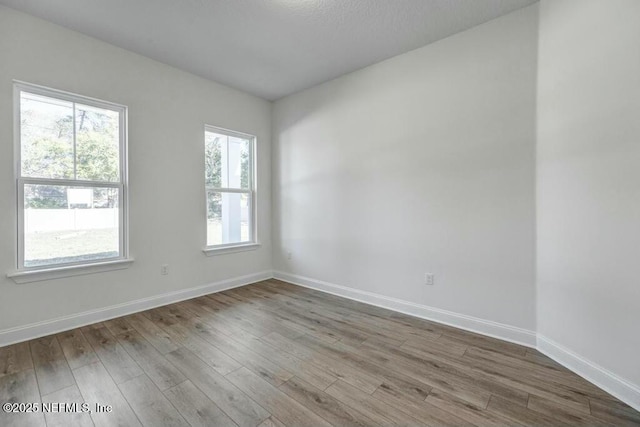 spare room featuring baseboards and wood finished floors