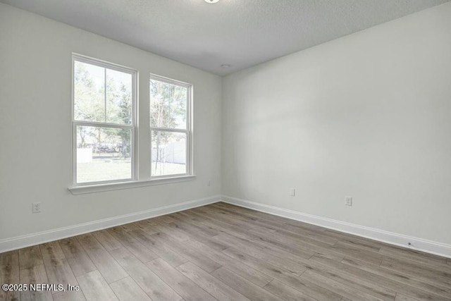 unfurnished room with light wood-type flooring and baseboards