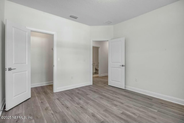 unfurnished bedroom with baseboards, visible vents, and light wood finished floors