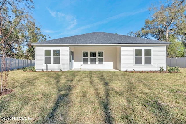 rear view of house featuring a shingled roof, a fenced backyard, and a lawn