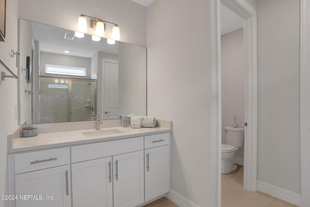 bathroom with tile patterned floors, walk in shower, vanity, and toilet