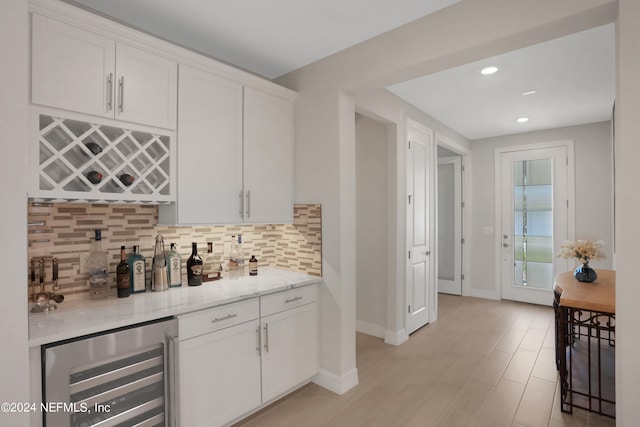 kitchen featuring light stone countertops, tasteful backsplash, beverage cooler, and white cabinets