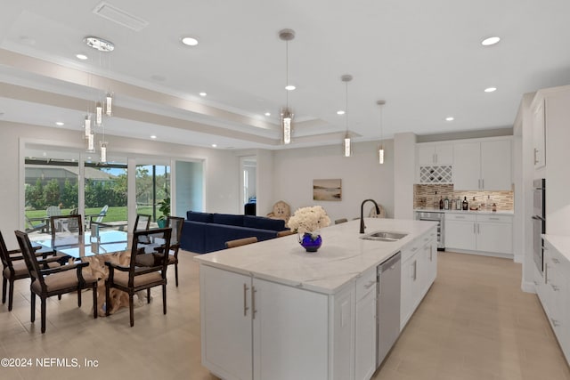 kitchen with a center island with sink, white cabinets, and decorative light fixtures