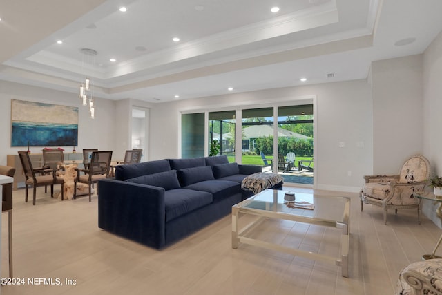 living room with a raised ceiling, crown molding, and light hardwood / wood-style flooring