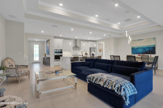 living room with a raised ceiling and ornamental molding