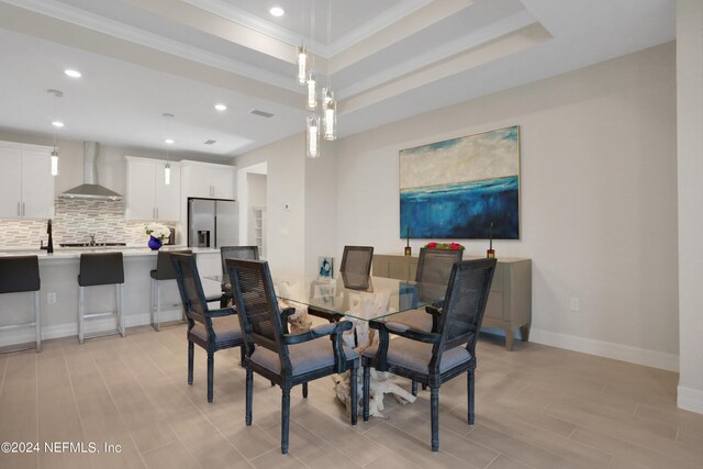 dining room featuring light hardwood / wood-style floors, a raised ceiling, and ornamental molding