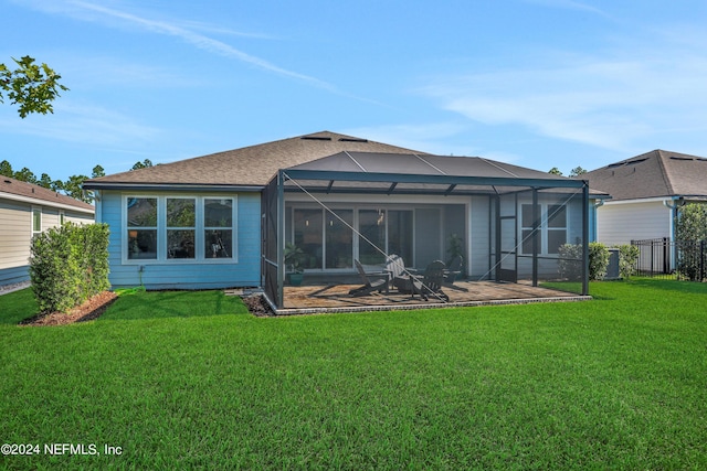 rear view of house featuring glass enclosure, a yard, and a patio area