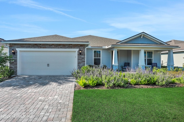 view of front of house featuring a garage, a front lawn, and covered porch