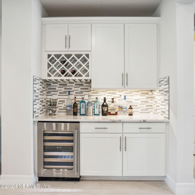 bar with white cabinets, beverage cooler, light tile patterned floors, and tasteful backsplash