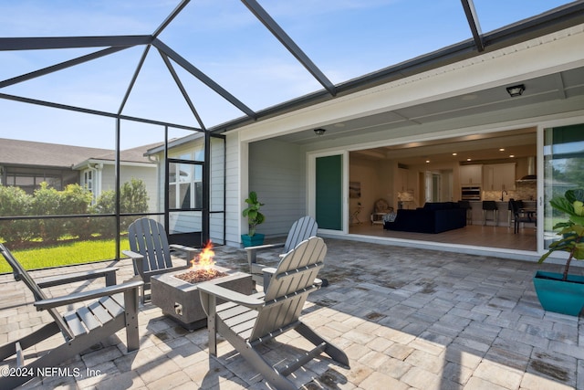 view of patio featuring glass enclosure and an outdoor fire pit