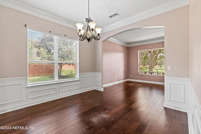 spare room featuring a notable chandelier, ornamental molding, and dark wood-type flooring