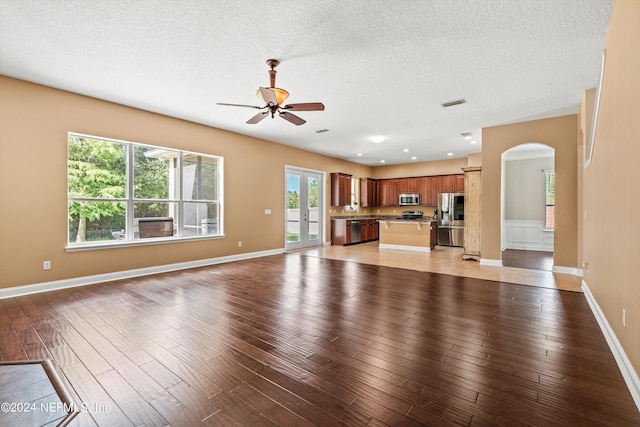 unfurnished living room featuring ceiling fan, a textured ceiling, and light wood-type flooring