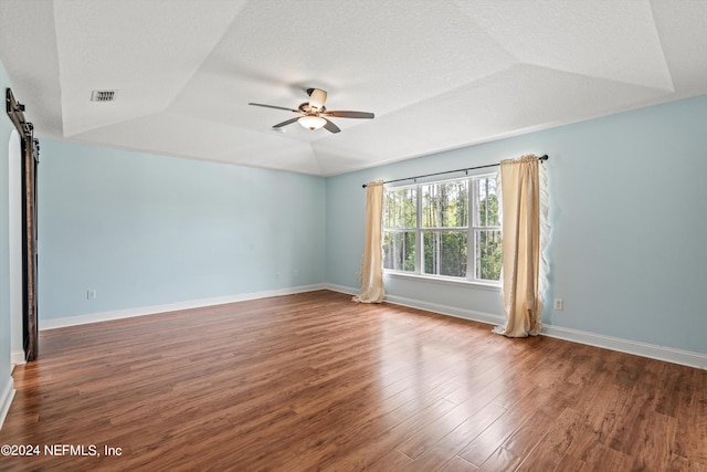 empty room featuring a textured ceiling, a raised ceiling, hardwood / wood-style floors, and ceiling fan