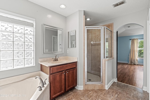 bathroom featuring shower with separate bathtub, wood-type flooring, vanity, and a textured ceiling