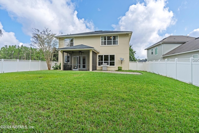 back of house featuring a lawn and a sunroom