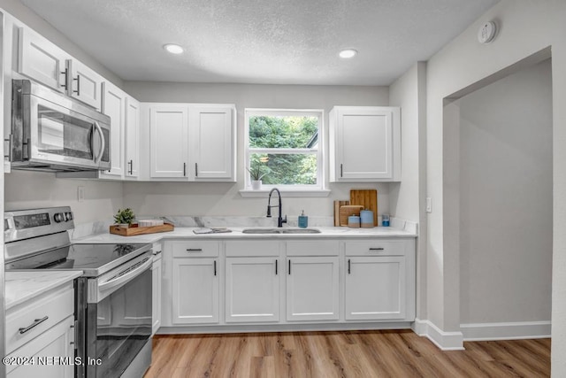 kitchen with white cabinets, light hardwood / wood-style floors, stainless steel appliances, and sink