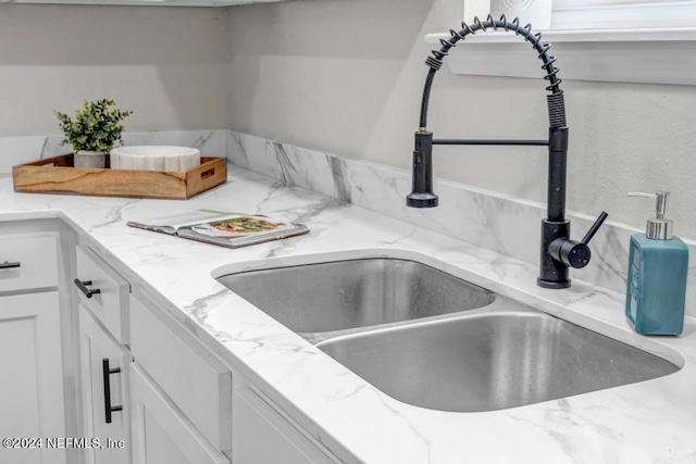 details featuring light stone countertops, sink, and white cabinets