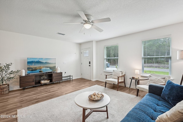 living room with a wealth of natural light, ceiling fan, hardwood / wood-style flooring, and a textured ceiling